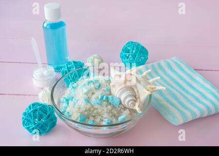 Soins DE SPA avec sel de mer et nettoyants. Lotion, crème et serviette de bain bleue sur fond rose. CONCEPT SPA, nettoyage du corps et de la peau, relaxation. Banque D'Images