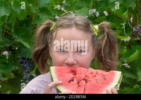 Bonne fille mange de la pastèque en été. Concept de bonne enfance, vacances, vitamines. Mise au point sélective, flou. Banque D'Images