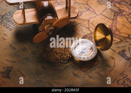 Ancienne découverte de boussole et avion en bois sur papier vintage carte du monde antique arrière-plan, la cartographie de style rétro Voyage de navigation géographique Banque D'Images