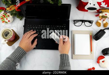 Achats en ligne de Noël. Achat de biens et de cadeaux pour la nouvelle année par Internet. Écrivez une liste et tenez une carte de crédit. Bureau avec ordinateur portable Banque D'Images