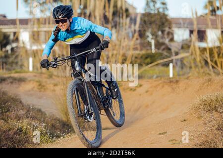 Sportswoman en casque noir et vêtements de sport bleus avec lunettes de vélo de montagne sur la piste d'entraînement Banque D'Images