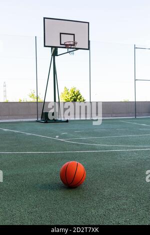 Ballon de basket-ball orange placé sur le terrain de sport moderne journée ensoleillée en été Banque D'Images