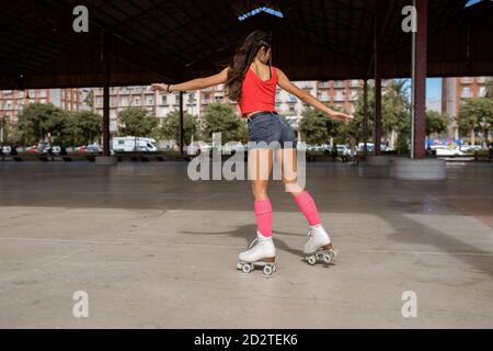 Concentration de l'équilibre féminin sur la jambe pendant le patinage à roulettes sur le sport terrain par jour ensoleillé en ville Banque D'Images