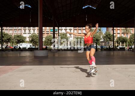 Concentration de l'équilibre féminin sur la jambe pendant le patinage à roulettes sur le sport terrain par jour ensoleillé en ville Banque D'Images
