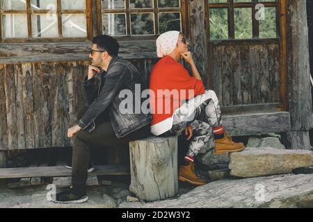 Couple assis dos à dos en face de la maison deux adultes sulky se sont détournés l'un de l'autre. Banque D'Images