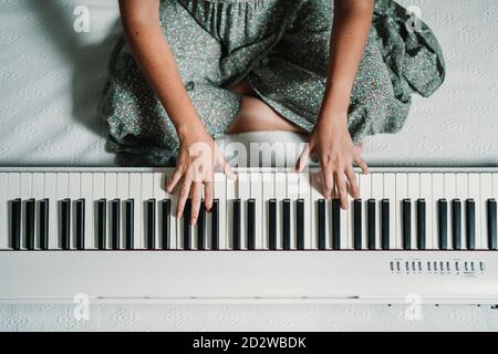 De dessus de la talentueuse musicienne ethnique jouant du piano tout en asseyez-vous dans un appartement moderne et répétez Banque D'Images