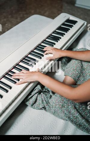 Musicienne ethnique talentueuse jouant du piano tout en étant assise dans un décor moderne appartement et répétition Banque D'Images