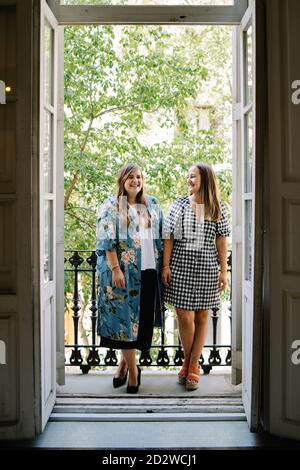 Des amies gaies avec une tenue élégante debout sur le balcon ensemble et profiter du week-end Banque D'Images