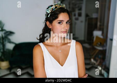 Femme tendre portant une délicate robe blanche debout dans un appartement moderne et regarder l'appareil photo Banque D'Images