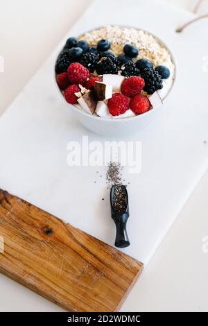 Grand angle de bol nutritif avec muesli et diverses baies dans un bol placé sur la table avec une serviette pour le petit déjeuner matin Banque D'Images