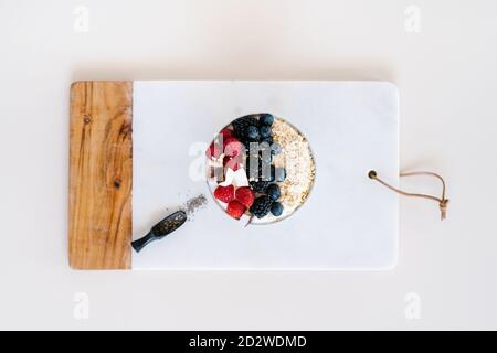 Grand angle de bol nutritif avec muesli et diverses baies dans un bol placé sur la table avec une serviette pour le petit déjeuner matin Banque D'Images