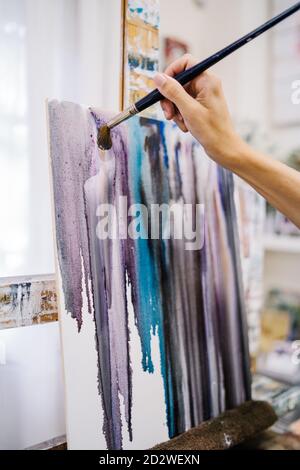 Rognez la vue d'une artiste féminine qui peint une image colorée avec des peintures tout en travaillant dans un atelier créatif Banque D'Images
