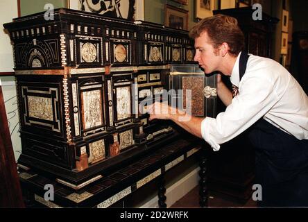 Le portier de Sotheby, Michael McLaughlin, regarde une armoire italienne en ébène et ivoire qui faisait partie d'une collection d'antiquités vendues par la maison de vente aux enchères appartenant à la recluse Ernest Onians, qui est décédée à l'âge de 90 ans en janvier. Il a transformé son moulin de Suffolk en une grotte d'antiquités d'Aladin qui a réalisé près d'un million aux enchères d'aujourd'hui. Banque D'Images