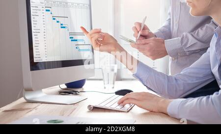 L'équipe de gestion de projet met à jour le calendrier de planification avec le diagramme de Gantt ordinateur au bureau pour communiquer sur l'avancement de la tâche et planifiez la prochaine étape Banque D'Images