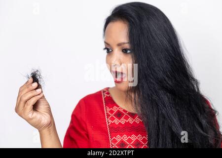 Portrait d'une femme indienne avec de longs cheveux face au problème de chute de cheveux, perte de cheveux, tenant les cheveux dans la main, problème de pellicules, alopécie. Banque D'Images