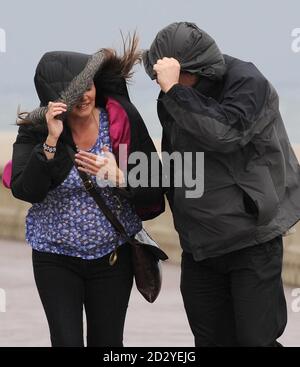 Les visiteurs de Scarborough couvrent leur visage tandis que des vents violents soufflent sur une tempête de sable sur North Bay et la promenade. Banque D'Images