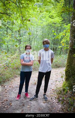 portrait de deux adolescents mâles portant des masques contre le covid se tenir ensemble sur un chemin dans une forêt sur un promenade les jours d'été Banque D'Images