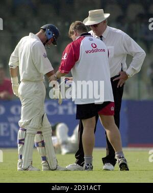 Angleterre physio Dean Conway (au centre) assiste à une blessure à l'hespérie d'Angleterre Nasser Hussain après qu'il a été frappé sur le bras par une balle de Wasim Akram du Pakistan pendant la dernière journée du premier test entre l'Angleterre et le Pakistan à Lahore. Banque D'Images