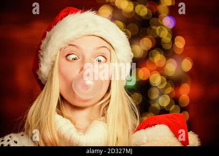 Crazy grimace. Faire des bulles avec de la gomme. Seulement amusant sur mon esprit. Fille du Père Noël, faisant de grands avec de la gomme à bulles. Funny face close up. Adorable woman blowing bubble. Fille de noël faites bubble-gum. Banque D'Images