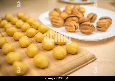 Petites boules de pâte à biscuits sur un panneau en bois et Une assiette de biscuits prêts à l'emploi un écrou bouilli lait condensé Banque D'Images