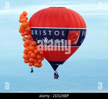 Mike Howard dangeant sous des centaines de ballons remplis d'hélium à la Bristol Balloon Fiesta. Howard, habillé comme son héros du diable dans une veste de dîner, s'est élevé à plus de 7 000 pieds mais n'a pas réussi à monter suffisamment haut pour battre le record mondial de 11 000 pieds en raison de la couverture de nuages lourds. Banque D'Images