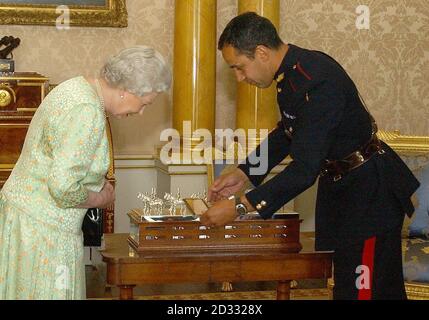 La reine Elizabeth II de Grande-Bretagne est présentée comme une pièce centrale en argent commandée par le Royal Regiment of Artillery par le sergent-major Derek Gilbert , au Palais de Buckingham. Banque D'Images