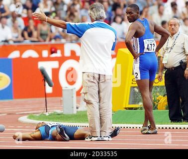 Jon Drummond (en bas) des États-Unis se trouve sur le dos, refusant de sortir de la piste après qu'il ait été disqualifié dans le quart-finale du 100m masculin aux Championnats du monde d'athlétisme à Paris, en France, le dimanche 24 août 2003. Banque D'Images