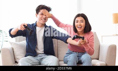 Couple japonais jouant Videogame assis sur canapé à la maison, Panorama Banque D'Images