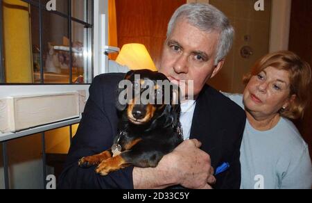 Gordon et Susan Musselwhite et leur dachshund Muffin avec la boîte aux lettres maintenant scellée dans la porte d'entrée de leur maison à Yealmpton, Devon. Le couple a perdu une affaire au tribunal du comté de Plymouth dans laquelle ils ont affirmé que leur animal avait été partiellement paralysé en sautant pour un dépliant de Safeways laissé pendre dans leur boîte aux lettres. Banque D'Images