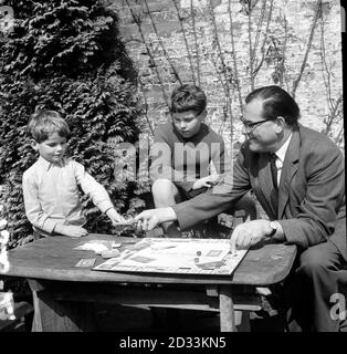 Reginald Maudling, chancelier de l'Échiquier qui prépare son prochain budget, se déchort un moment pour jouer le jeu populaire, monopole avec ses fils Edward.9 (au centre) et William, 7 ans, dans sa maison de campagne à Bedwell Lodge, Essendon, Herts.Au cours du jeu Edward a demandé "pourquoi ne pas acheter Fleet Street?", une requête qui a apporté une rafale de rires de la presse hommes présents. Banque D'Images