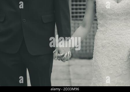 Couple de mariage tenant les mains de gros plan en noir et blanc Banque D'Images