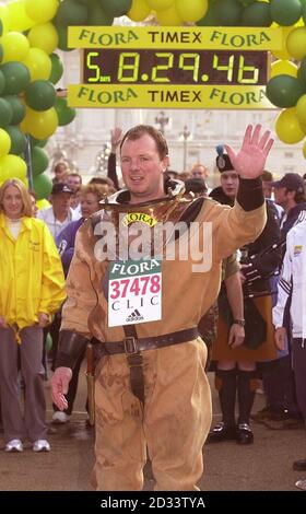 Lloyd Scott franchit la ligne d'arrivée du marathon de Londres, Lloyd, le coureur de marathan le plus lent de l'histoire, a 'couru' le parcours portant un costume de plongée antique en six jours. Lloyd espère avoir grandi dans la région de 100,000 en faveur du cancer et de la leucémie dans l'enfance grâce à ses efforts. Banque D'Images