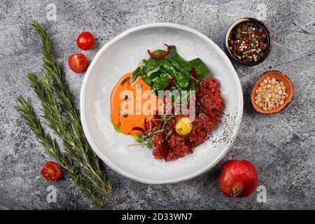 Tartare de bœuf avec jaune d'œuf, oignon et herbes. Cuisine française. La vue du dessus. Banque D'Images