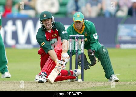 Heath Streak au Zimbabwe balaie une balle du lanceur sud-africain Paul Adams, alors que le gardien de rue Mark Boucher (à droite) regarde pendant le 6e match de la série NatWest, à Sophia Gardens, à Cardiff. Banque D'Images