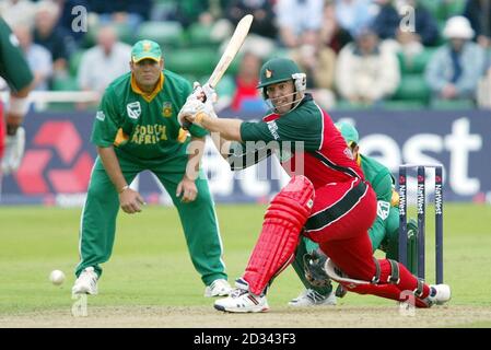 Heath Streak au Zimbabwe balaie une balle du lanceur sud-africain Paul Adams alors que Jacques Kallis, le fianteur de patinage, regarde (à gauche) pendant le 6e match de la série NatWest, à Sophia Gardens, à Cardiff. Banque D'Images