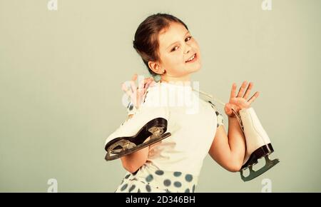 Vous permet d'aller patiner. Heureux l'enfant avec les patins accroché sur le cou. Petite fille profiter du patinage sur glace. Danse sur glace. Le patinage artistique. Piscine skatepark ou patinoire. Activités d'hiver. Jour de glace, copiez l'espace. Banque D'Images