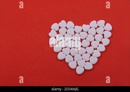 Forme de coeur à partir de pilules de coeur, pilules de coeur sur un fond rouge. Des médicaments qui aident les gens. Banque D'Images