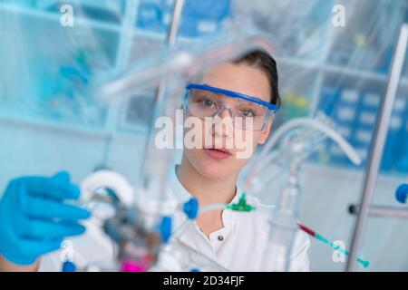 Jeune femme dans un laboratoire pharmacologique. Développement d'un médicament antiviral. Pandémie COVID-19 Banque D'Images