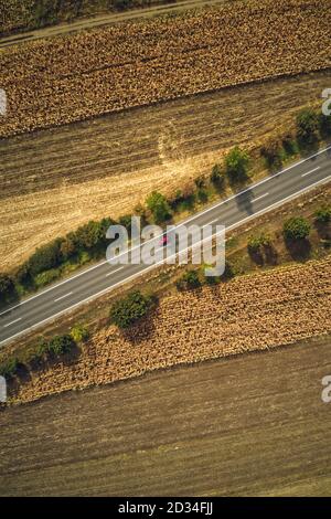 Monovoiture rouge sur la route, vue de dessus de drone pov. Photographie aérienne de véhicule sur la route à travers la campagne en été. Banque D'Images