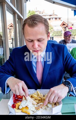 A Young Man Eating Fish and Chips, Londres, Royaume-Uni. Banque D'Images