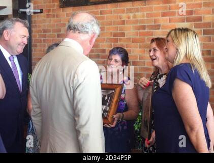 Screengrab tiré de la vidéo PA du Prince de Galles lors de son voyage à Bundaberg, recevant une photo de quatre sœurs avec lesquelles il avait l'habitude de passer ses week-ends quand il avait 17 ans. Banque D'Images