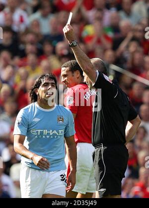 Carlos Tevez de Manchester City (à gauche) affiche une carte jaune Par l'arbitre Martin Atkinson Banque D'Images