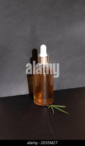 Bouteilles en verre et compte-gouttes D'HUILE CBD, teinture de THC et feuilles de cannabis sur fond noir. Production en laboratoire de cosmétiques avec de l'huile CBD. Banque D'Images