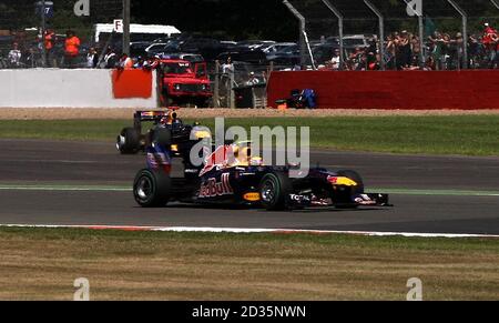 Sebastian Vettel, de Red Bull Racing (en haut), avec son pneu qui sort alors que Mark Webber roule avant le Grand Prix britannique de Santander sur le circuit de Silverstone, à Northampton. Banque D'Images