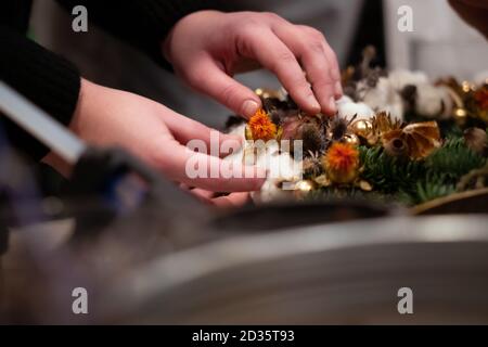 Couronne de Noël Atelier de tissage. Femme de couronnes de décoration mains faites de branches d'épinette, cônes et diverses décorations organique sur la table Banque D'Images