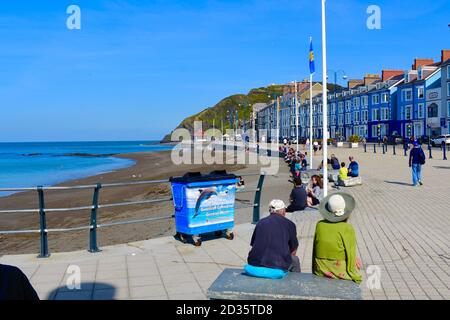 Une vue sur les différents hôtels victoriens qui bordent Marine Terrace qui donnent sur la mer à Aberystwyth. Les gens se reposant au soleil. Banque D'Images