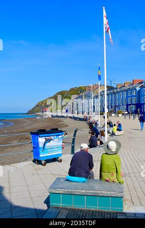 Une vue sur les différents hôtels victoriens qui bordent Marine Terrace qui donnent sur la mer à Aberystwyth. Les gens se reposant au soleil. Banque D'Images