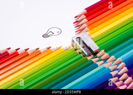 Crayons de couleur disposés formant une fermeture éclair d'ouverture révélant une lumière ampoule comme symbole de créativité Banque D'Images