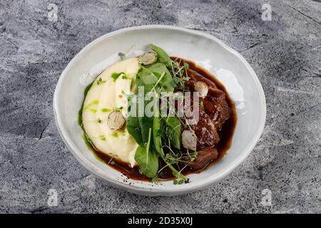 Joues de veau en sauce avec pommes de terre et chou, décorées avec des herbes Banque D'Images