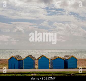 Huttes de plage sur la plage est de Littlehampton avec la mer à distance sous un ciel nuageux et spectaculaire Banque D'Images